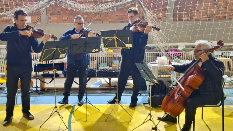 Na imagem, da esquerda para a direita, os violinistas Paulo Barcelos e Geraldo Moori, o violista Delmar Breunig e violoncelista Deolindo de Azambuja. Todos eles estão com roupa escura e somente o da direita está sentado. 