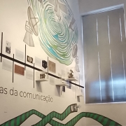 Uma parede branca escrita ''Memórias da comunicação'', da exposição Paralelos.