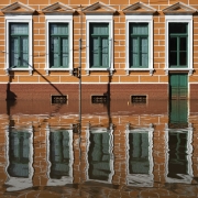Fachada de um prédio histórico refletida na água da enchente, que cobre parcialmente as janelas inferiores e a porta.