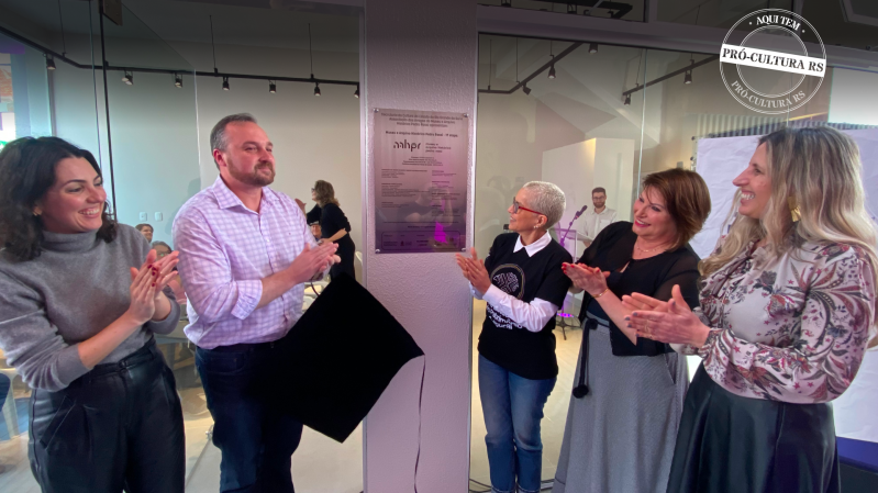 A secretária Beatriz Araujo e outras quatro pessoas batem palmas após o descerramento da placa de inauguração