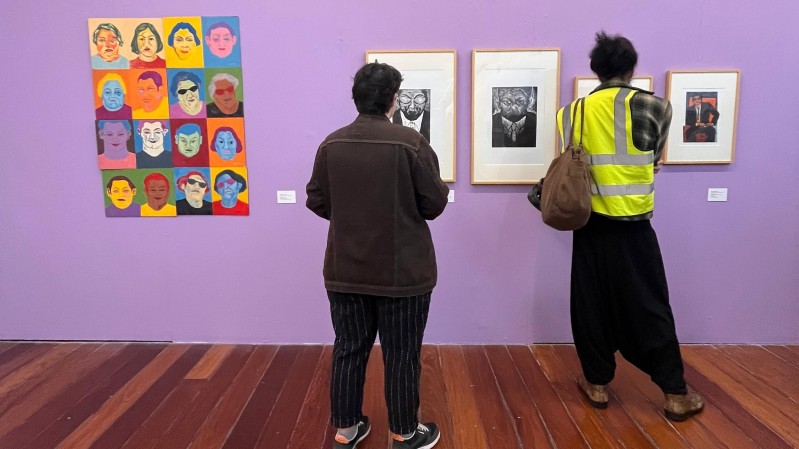 Duas pessoas observam obras em exposição no MACRS