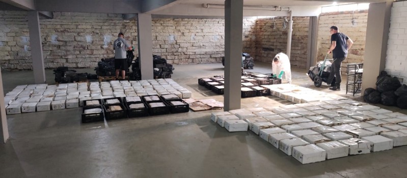 Dois funcionários carregam e organizam caixas e maços de itens