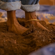 A imagem mostra os pés de uma pessoa descalça pisando na terra.