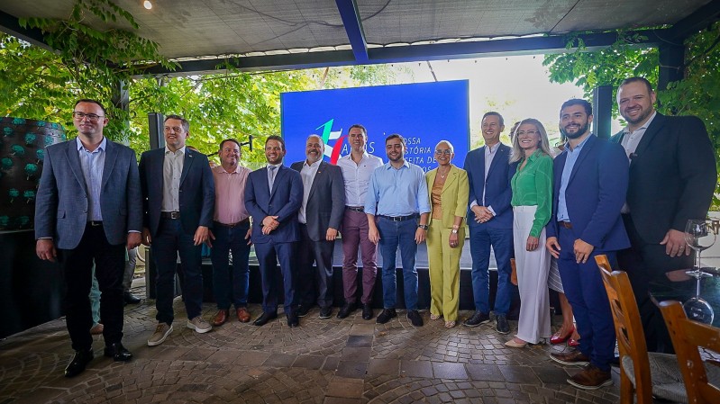 Doze pessoas estão em pé, lado a lado, sorrindo para a câmera, no lançamento da Rota Pipa Parade 2025