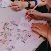 A imagem mostra as mãos de uma pessoa desenhando sobre uma mesa.