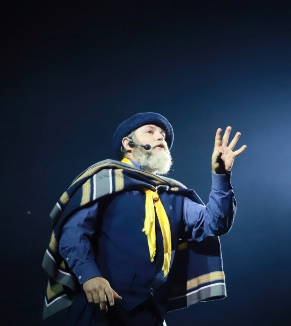 Um homem com trajes gaúchos fala ao microfone