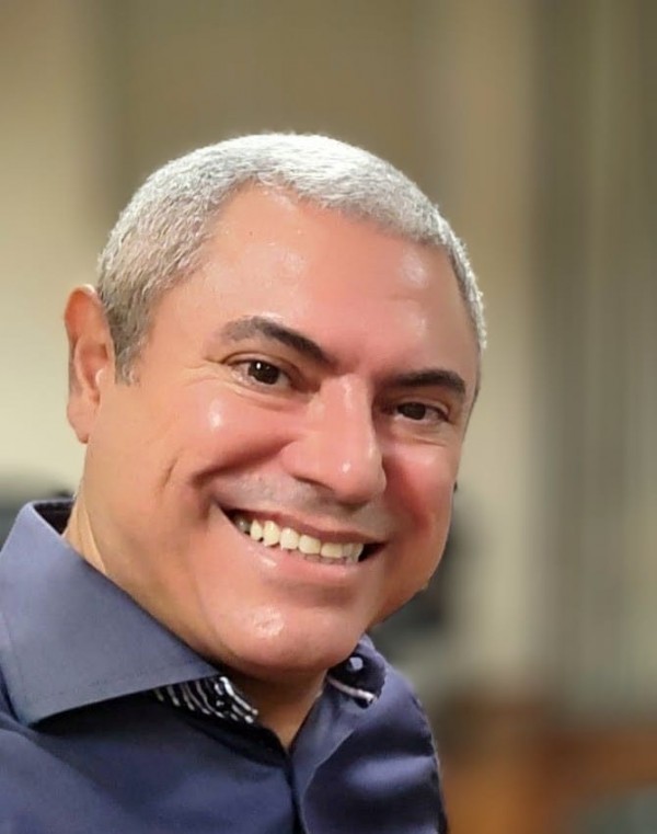 Um homem branco de camisa azul sorri