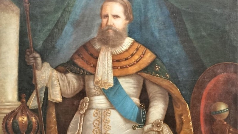 Retrato a óleo Dom Pedro II, com uma expressão serena e vestindo uma roupa elaborada. A composição do quadro apresenta-o como figura central da imagem. Seu olhar está direcionado para o espectador. O retrato sugere um momento de dignidade e poder. D.Pedro II é retratado com aparência madura, com uma barba bem cuidada e um olhar direto, sugerindo confiança e autoridade. Sua vestimenta é rica em detalhes, com tecidos de tons claros que sugerem requinte e ostentação, como as texturas das mangas e da faixa, lembrando veludos e cetins. As cores são ricas em tom e texturas, que resultam em uma qualidade realista. O ambiente do retrato é representado por um fundo escuro e neutro, que realça a figura principal. A ambientação e as cores evocam uma atmosfera formal, rica e majestosa, adequada para representar um monarca. A iluminação é de cima para baixo e suave, que resulta em uma atmosfera profunda e com destaque para os traços faciais da figura central.