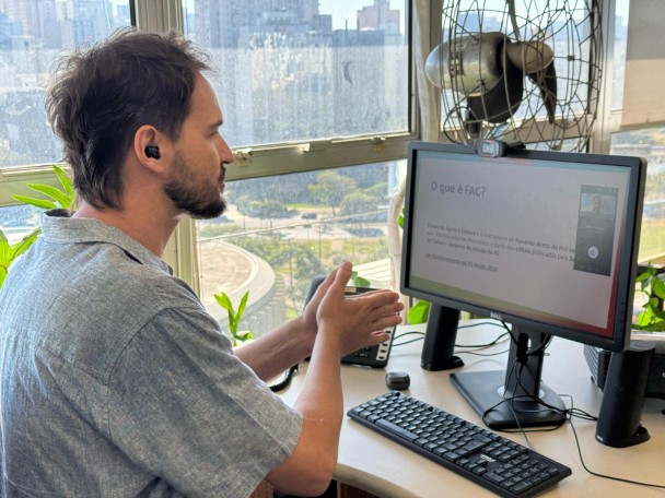 Imagem mostra Rafael Balle diante de uma tela de computador. 