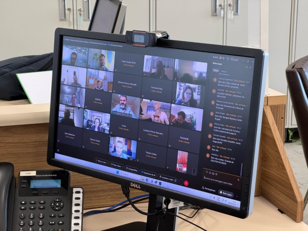 A imagem mostra a tela de um computador com diversas pessoas em sala de reunião virtual. 