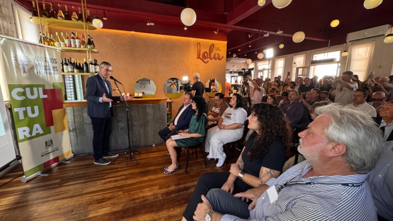 Em uma sala lotada de pessoas sentadas, o secret&aacute;rio da Cultura Eduardo Loureiro est&aacute; de p&eacute; ao microfone. Atr&aacute;s dele h&aacute; um banner com o logo dos 400 anos das Miss&otilde;es jesu&iacute;ticas guaranis e a palavra "Cultura" em caixa alta.