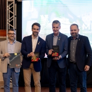 Quatro homens em trajes esporte posam para foto. Dois deles exibem medalhas de honra ao mérito: Eduardo Leite e Eduardo Loureiro, ao centro.