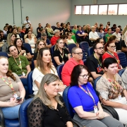 A imagem mostra pessoas sentadas em um auditório. 