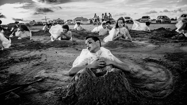 Obra pessoas enterradas com na areia com maquiagem sombria