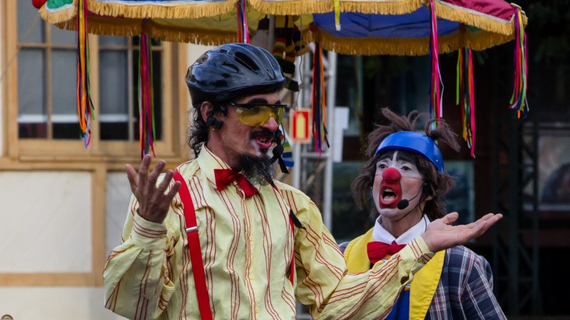 Palhaços de óculos, capacete de bicicleta, com maquiagem simples de palhaço e acessórios de gala